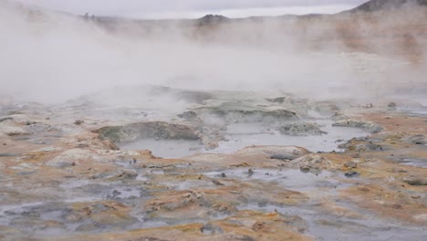 vapor, geysers and mud pots in active geothermal area in landscape of iceland