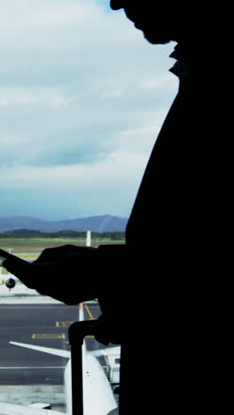 un hombre de negocios enviando mensajes de texto por teléfono móvil en el aeropuerto.