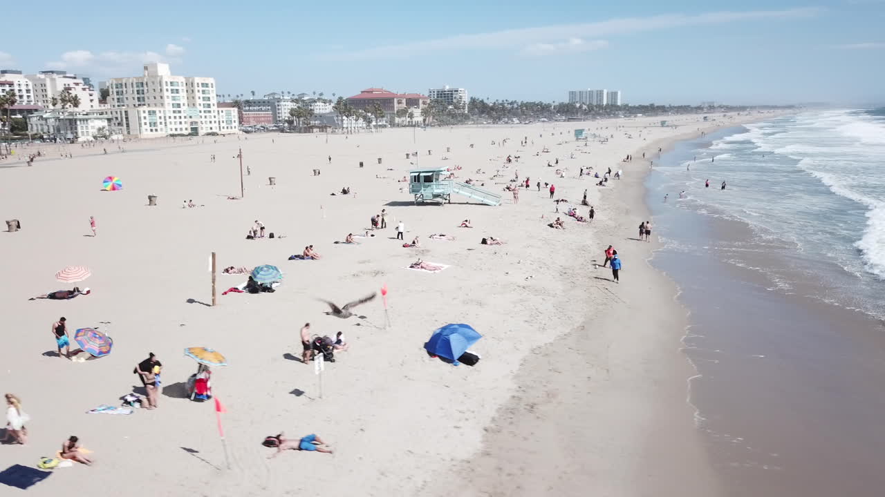 пляж в летнее или весеннее время с посетителями, которые наслаждаются волнами