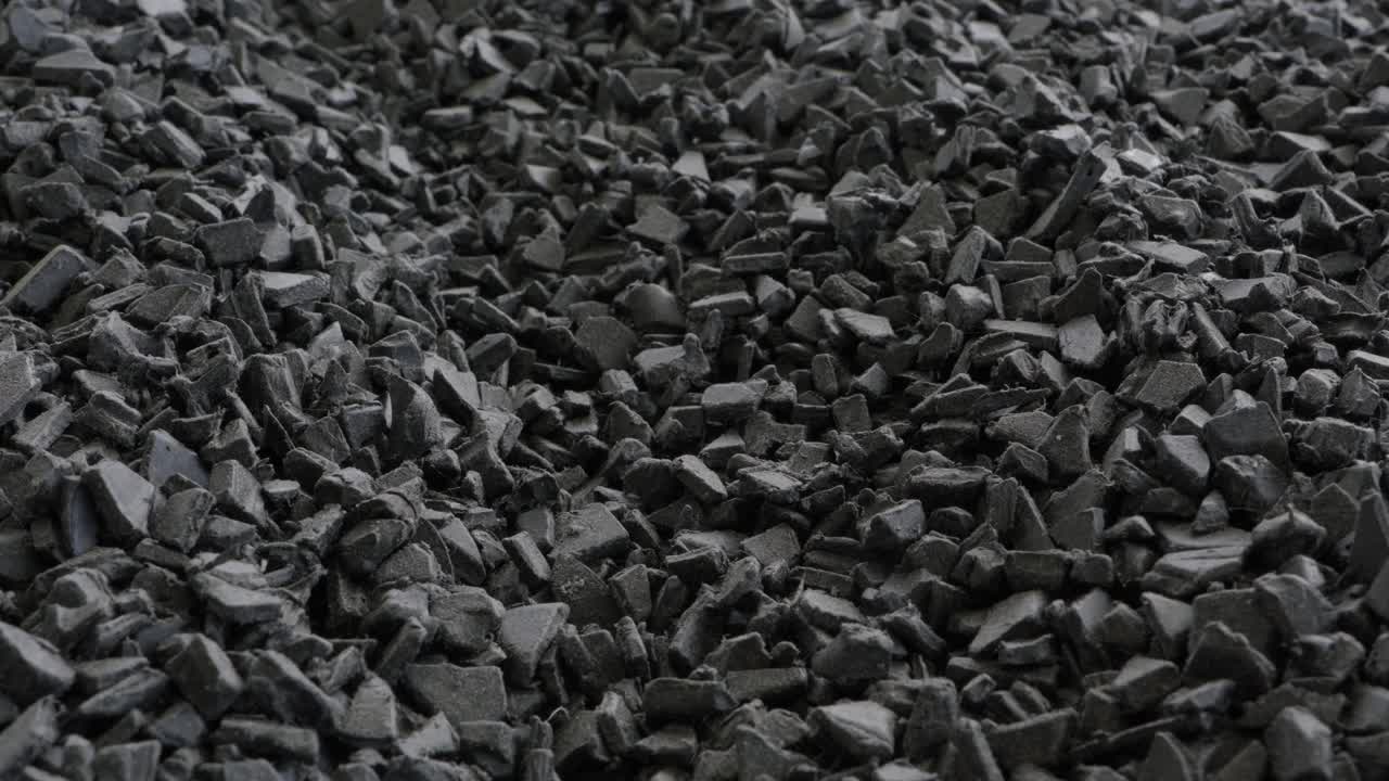 Плотная куча измельченных черных пластиковых хлопьев и стружки после промышленного процесса измельчения.