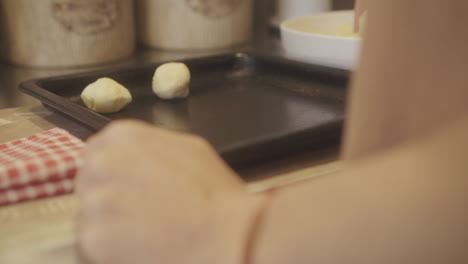 manos preparando pan tradicional de chipa en una bandeja de horneado en una cocina acogedora, mostrando el proceso de hacer y disfrutar de este querido regalo en casa