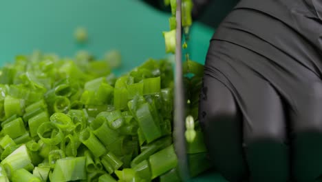 close-up of a chef's gloved hand quickly slicing celery on a board