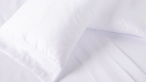 camera slowly zooms into fresh white bedding in soft morning light