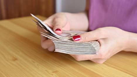 woman with red fingernails counting thai baht banknotes.