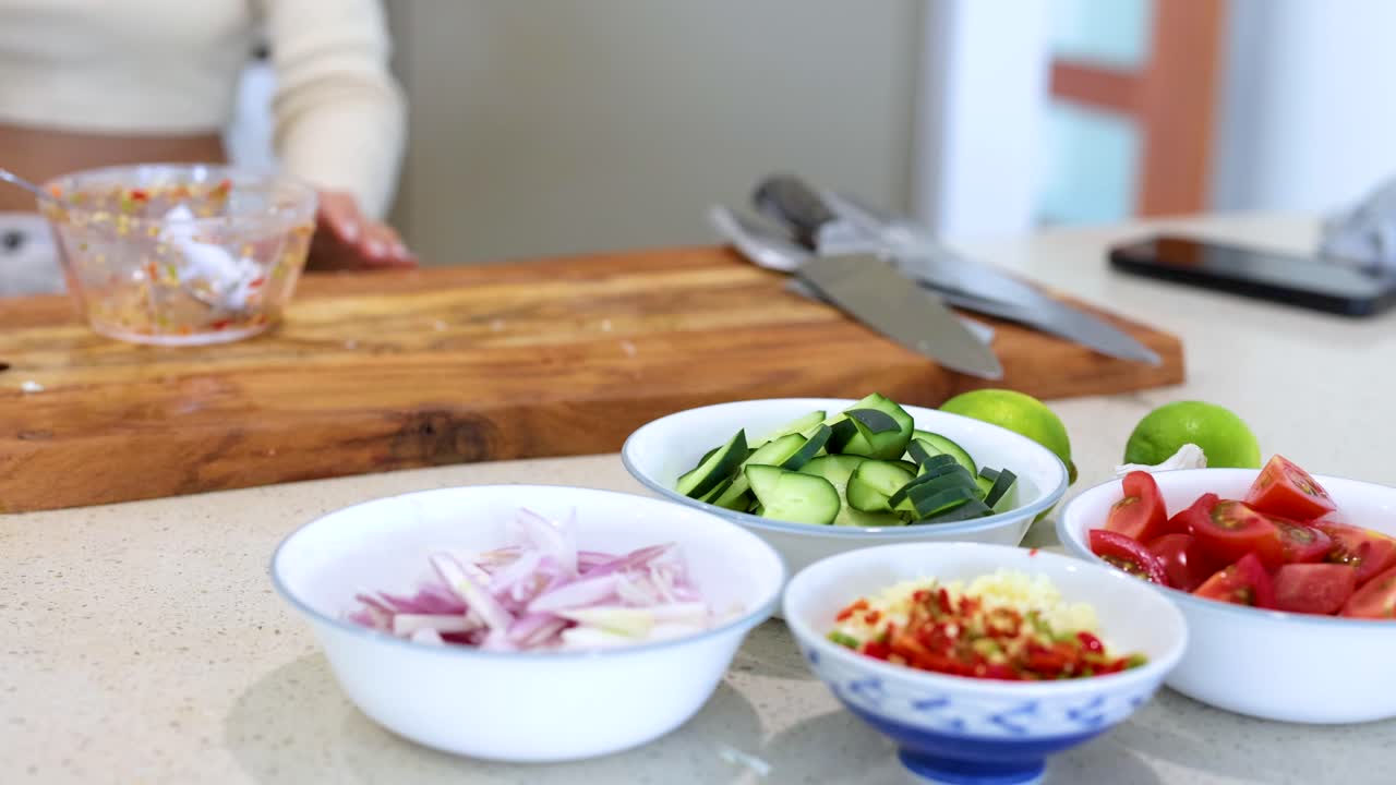 A person arranges sliced vegetables on a countertop in a bright kitchen setting, emphasizing freshness and culinary preparation