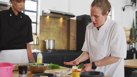 caucasian female chef teaching diverse group wearing face masks