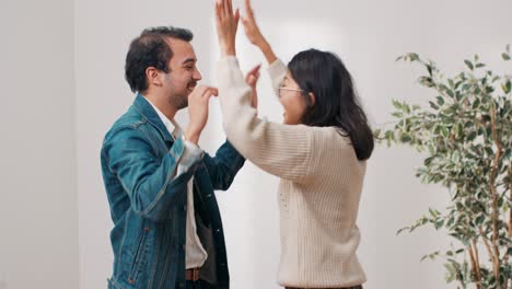 couple in love moves into new purchased apartment, they are happy to rent a house, they high-five hug, the man lifts the woman with joy, happiness