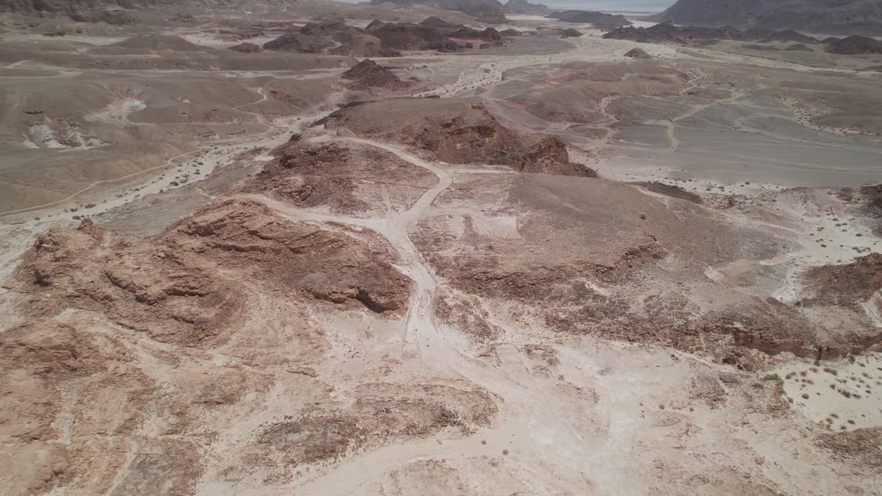 vista aérea sobre acantilados y una carretera desértica en el valle de timna, israel - marcha atrás, inclinación, disparo de drones
