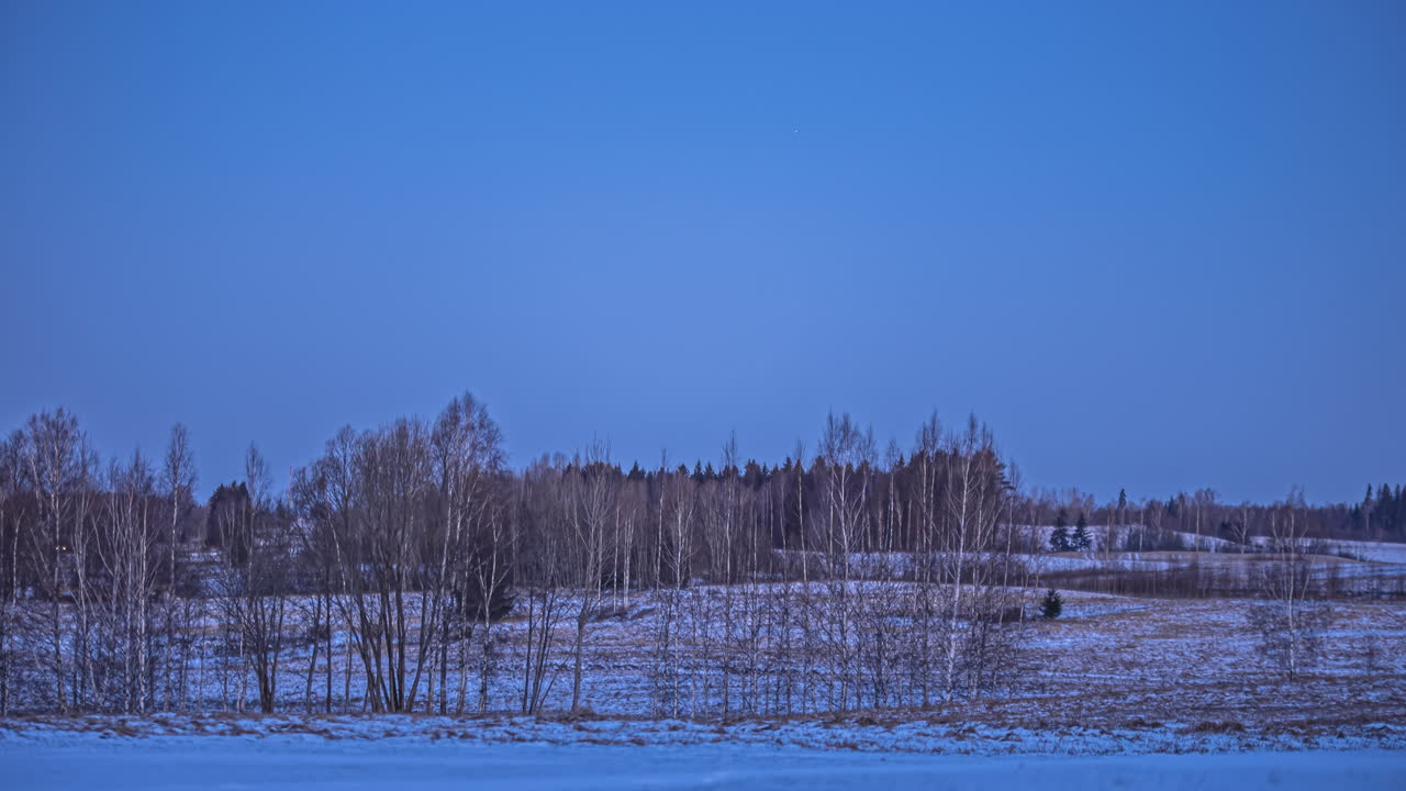 겨울 일몰 시간 동안 색깔 있는 하늘에 구름을 날리는 눈 덮인 풍경의 4k 시간 경과