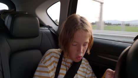 child playing on smartphone in car backseat