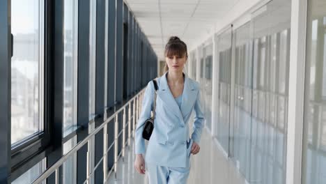 beautiful girl walking down the hall receives a joyful message on a smartphone