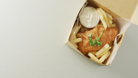 video of fish and chips with dip in takeaway food box, with copy space on white background