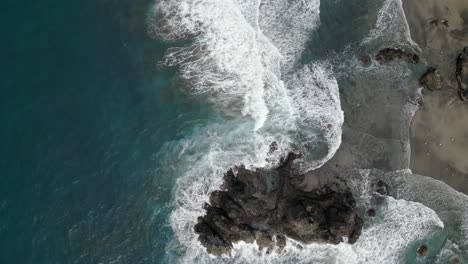 Aerial-view-of-a-back-sand-beach-and-turquoise-water