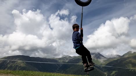 cute young boy swinging by in slow motion on top of a mountain