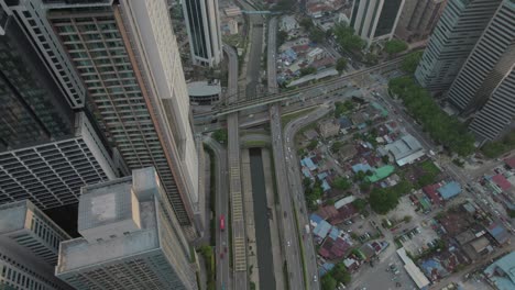 top-down aerial view of kuala lumpur's bustling downtown district, highlighting busy highways, bridges, and towering skyscrapers in the heart of a vibrant urban environment.