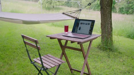 homeoffice setting with laptop on table in garden next to hammock