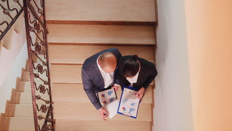 top view of businesspeople holding clipboards looking on graphs