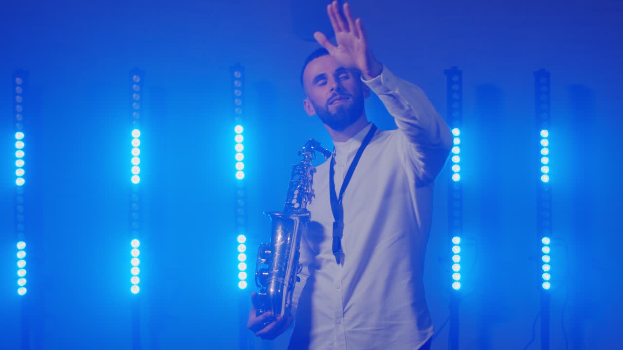Liveoptræden med en saxofonist med saxofon, der danser på en koncertscene med lys.