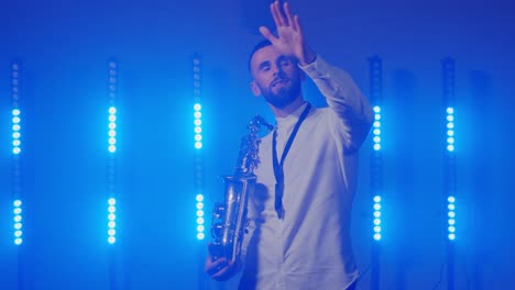actuación en vivo del saxofonista hombre con saxofón, bailando en el escenario del músico de concierto con luces