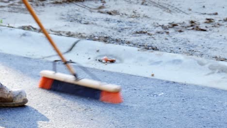 worker cleaning road with large brush