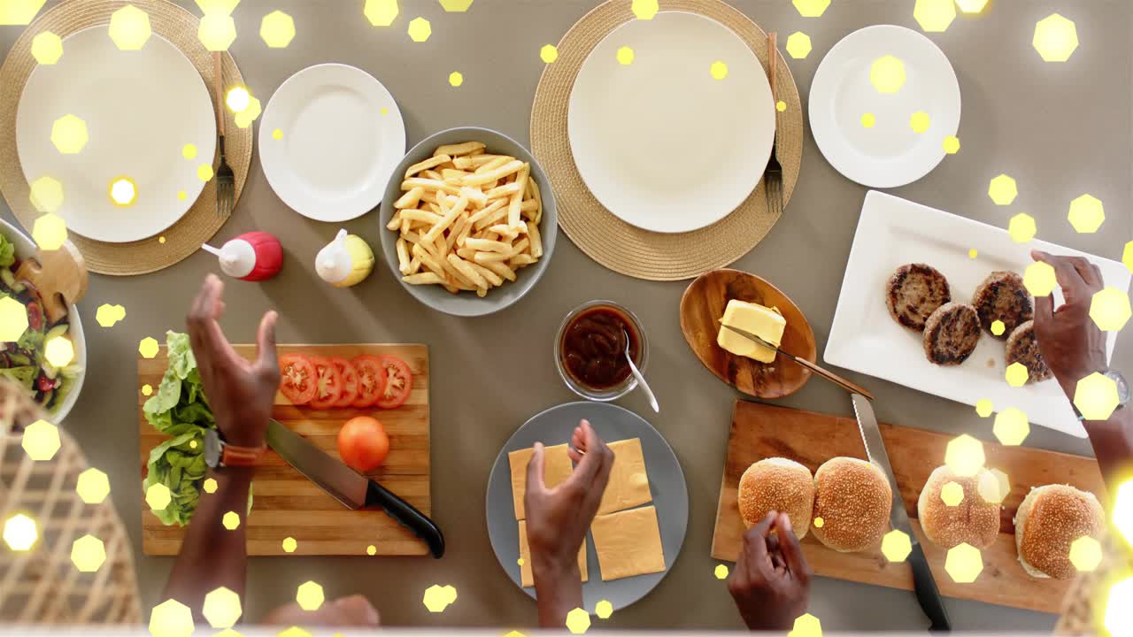 Son reaching lettuce father lifting patties building burgers for meal gold bokeh moving over hands