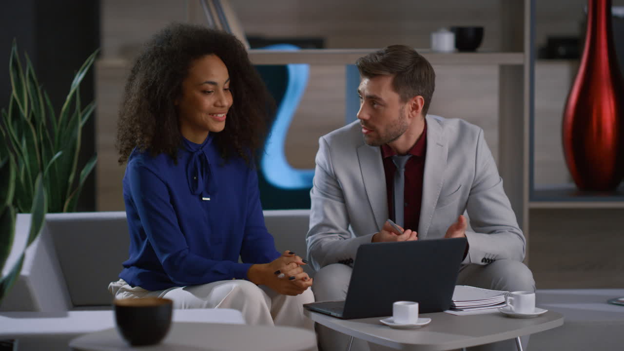 Creative multiracial business couple working together researching laptop in cafe