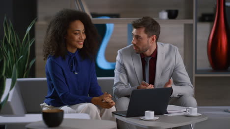 Creative-multiracial-business-couple-working-together-researching-laptop-in-cafe