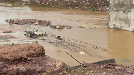 a bridge damaged by floodwaters, with parts of the structure swept away and reinforcing iron rods exposed showing the bad quality of bridge construction and infrastructure maintenance in india