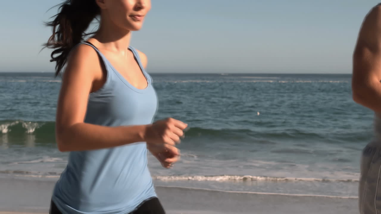 Donna con il suo partner che corre sulla spiaggia