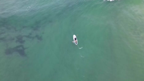 drone video of a paddleboarder in the waves