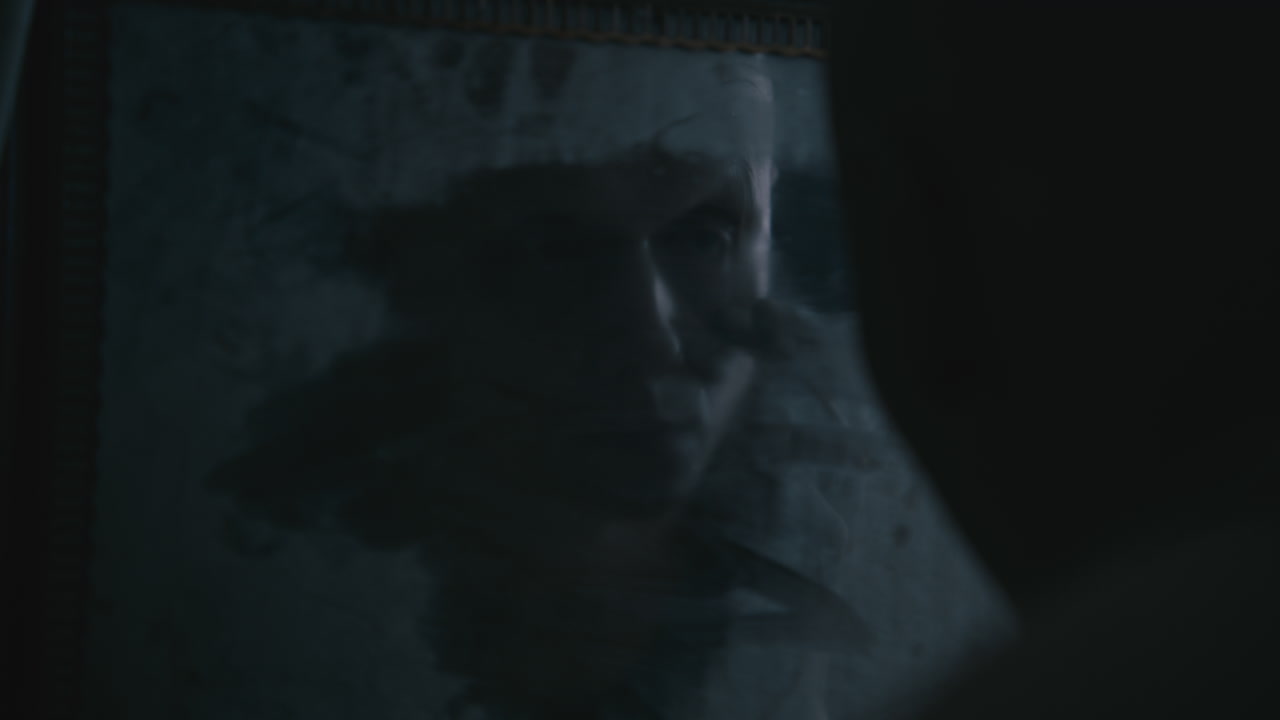 Pale bald skinny man looks into the mirror in the creepy old bathroom at night