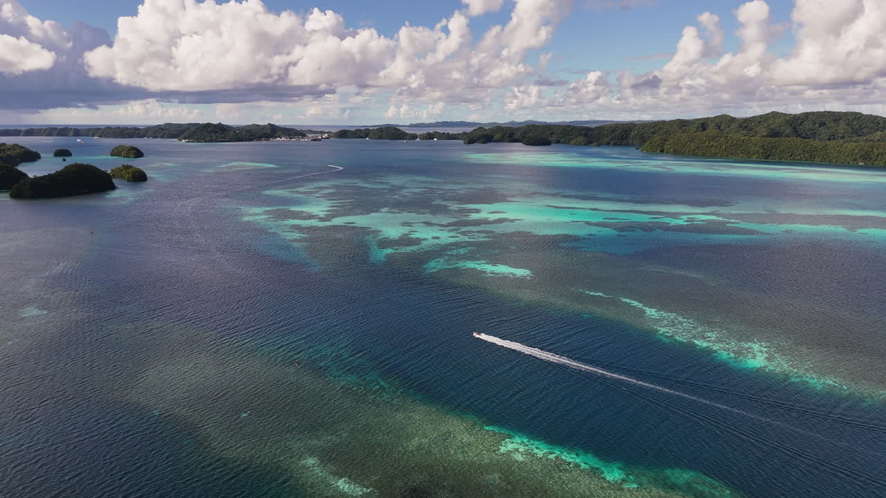 Elegant drone orbiting shot circling and revealing the vivid aqua ocean and green-covered terrain in Palau. boat in the water. Orbiting wide drone shot