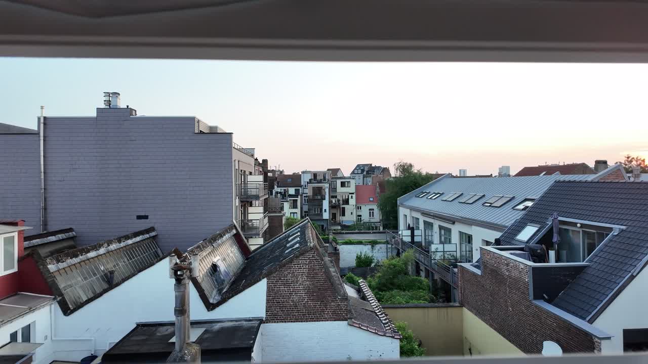 Forward camera motion reveals rooftops at sunset in Brussels