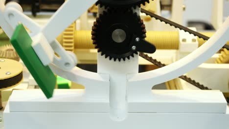 close-up view of mechanism with black plastic gears and axis with small plate rotating on the circle. media. different working devices collection presented on the robotics forum exhibition