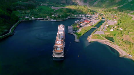 Big-cruise-ship-anchored-in-beautiful-small-town-flam-in-Norway,-aerial