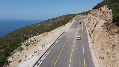 Drohnenansicht-Von-Autos,-Die-Auf-Einer-Bergstraße-Neben-Dem-Meer-Fahren