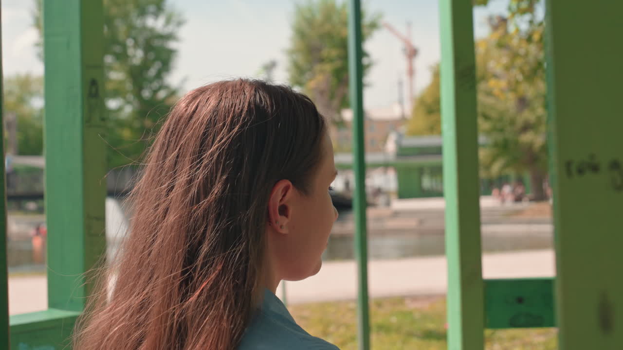 calm woman adjusting hair in scenic park, sunlit park setting with woman readying for photograph, woman in casual attire fixing her hair before capturing picture amid sunny park surroundings