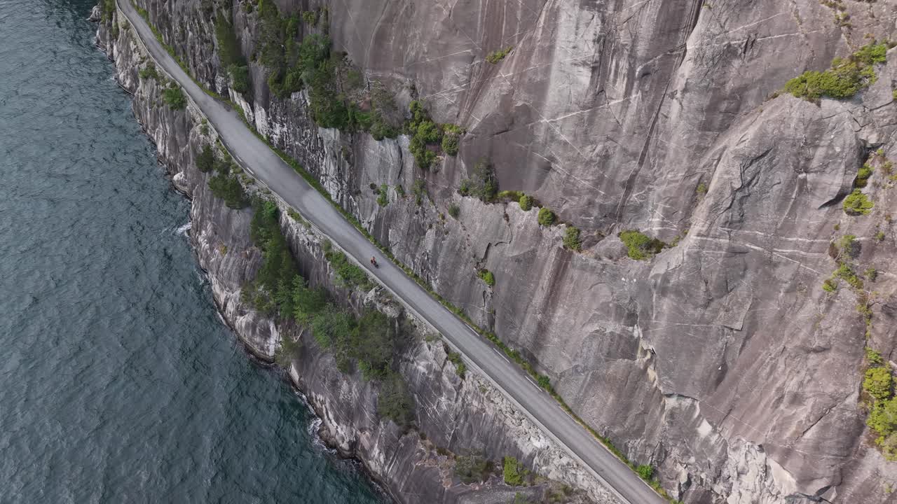 Person Biking On The Cliffside Road Along The Fjord In Norway. - aerial shot