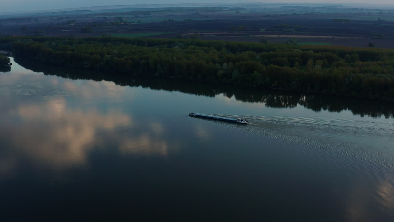 크로아티아 부코바르에서 새벽 실루엣을 배경으로 다뉴브 강을 항해하는 화물 운송선