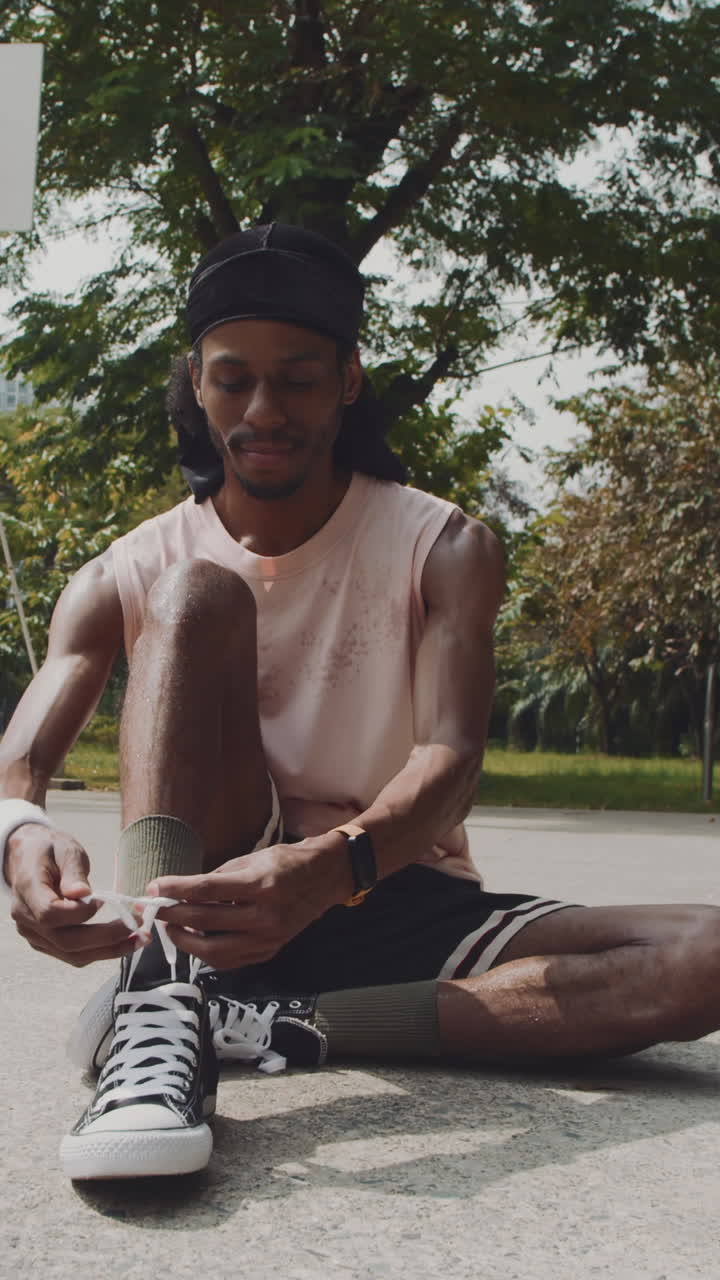 Vertical of Sportsman Tying Shoelaces on Streetball Court