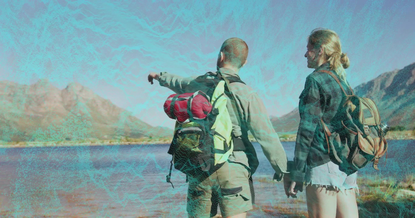 Pareja de mochileros viajeros tomados de la mano caminando por aguas poco profundas y señalando picos sobre un lago de montaña