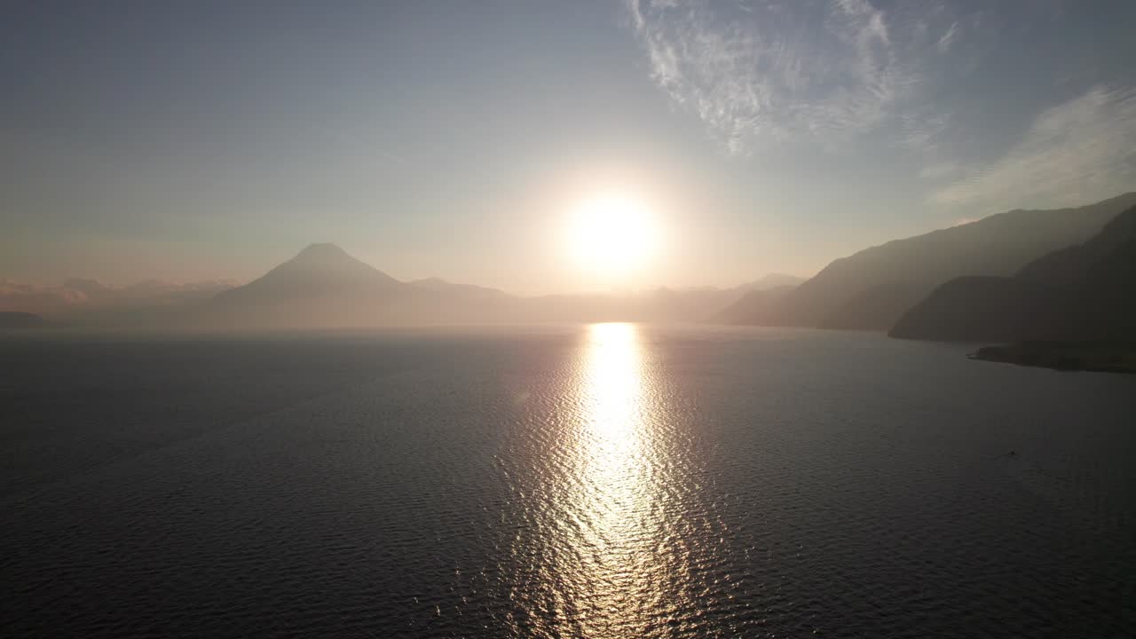 Sunset between volcanoes on serene tropical lake, 4K aerial nature shot, Lake Atitlan, Guatemala