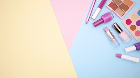 los productos de maquillaje pastel se mueven en la esquina derecha del fondo pastel - detenga el movimiento