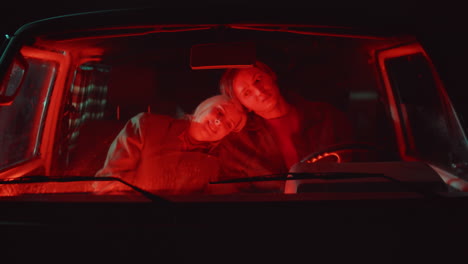 affectionate couple sitting in car at night