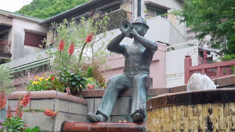 bronze statue of a man playing a trumpet at a fountain in a japanese town