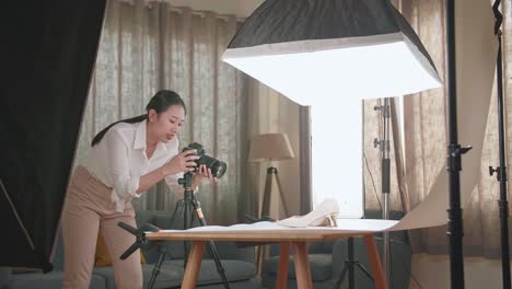 asian female photographer checking the photos of women's shoes after taking them in home studio