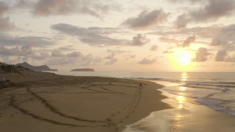 silhouette of rocks at ponta da calheta with female riding horse into sunrise