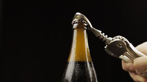 apertura de botella fría de cerveza con abridor de botella. condensado y gotas de agua