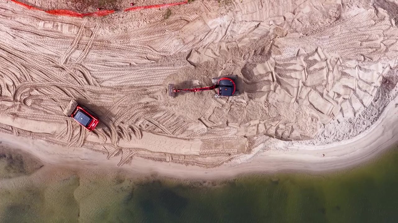 Filmato aereo dall'alto mostra macchinari pesanti che spostano sabbia per la gestione costiera su una spiaggia australiana