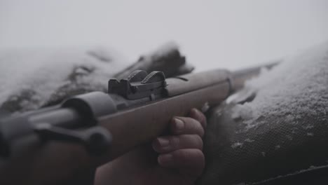 person picking old vintage riffle from world war in snow area